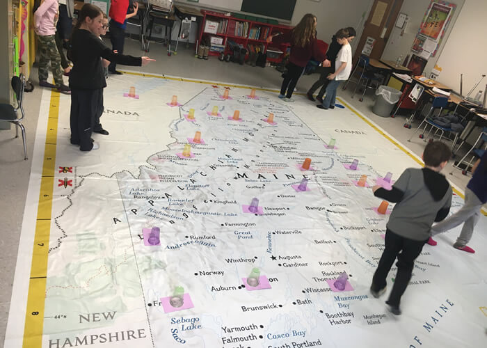 Recent budget for the Rangeley Lakes Regional School.  Image of students with floor size map of Maine.