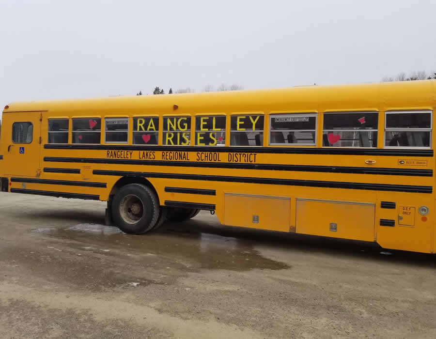 Rangeley Lakes Regional School bus with "Rangeley Rises" in the bus windows.